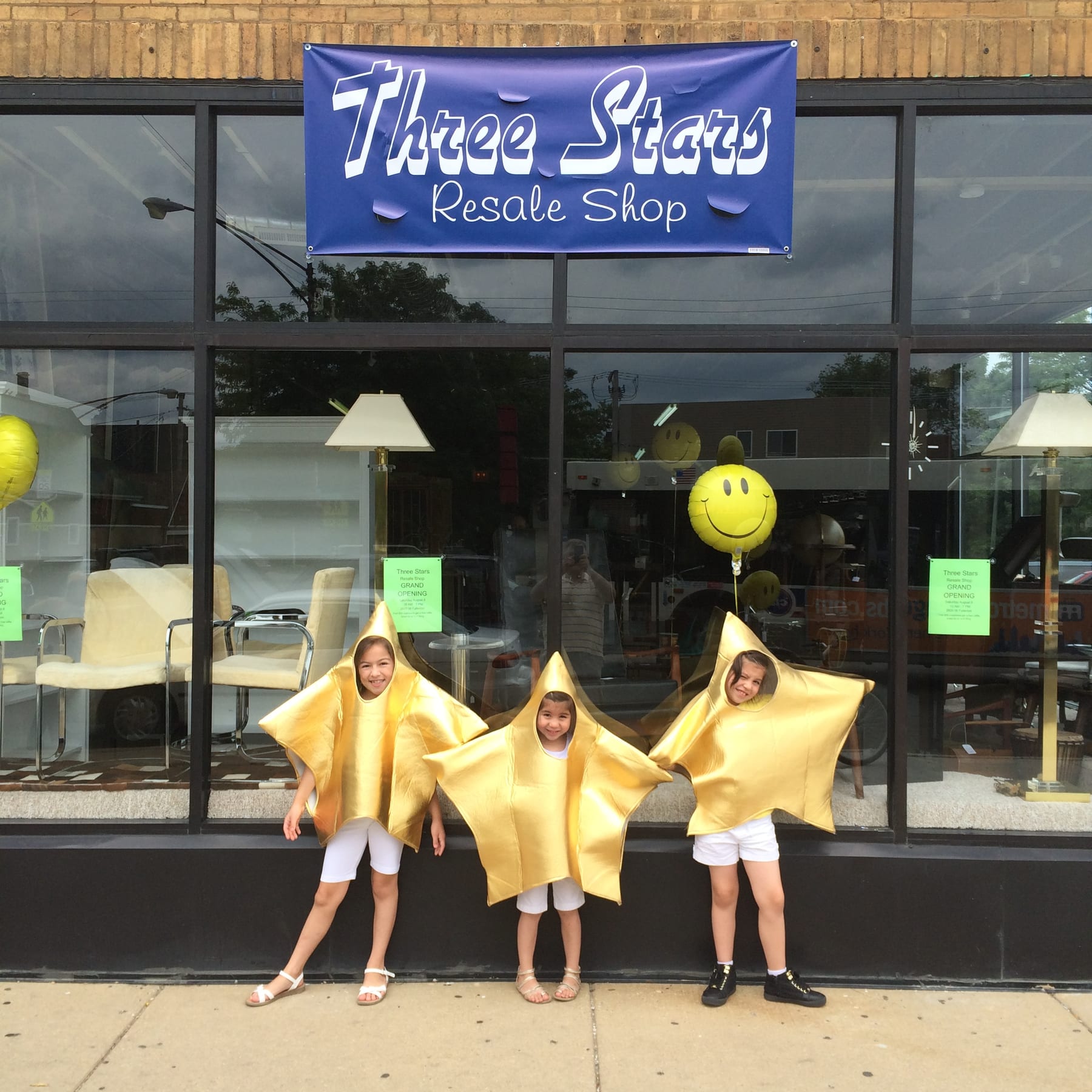 Andrea, Jayne, and Alani Reyes — the three stars — outside the original Three Stars Resale Shop in star costumes.