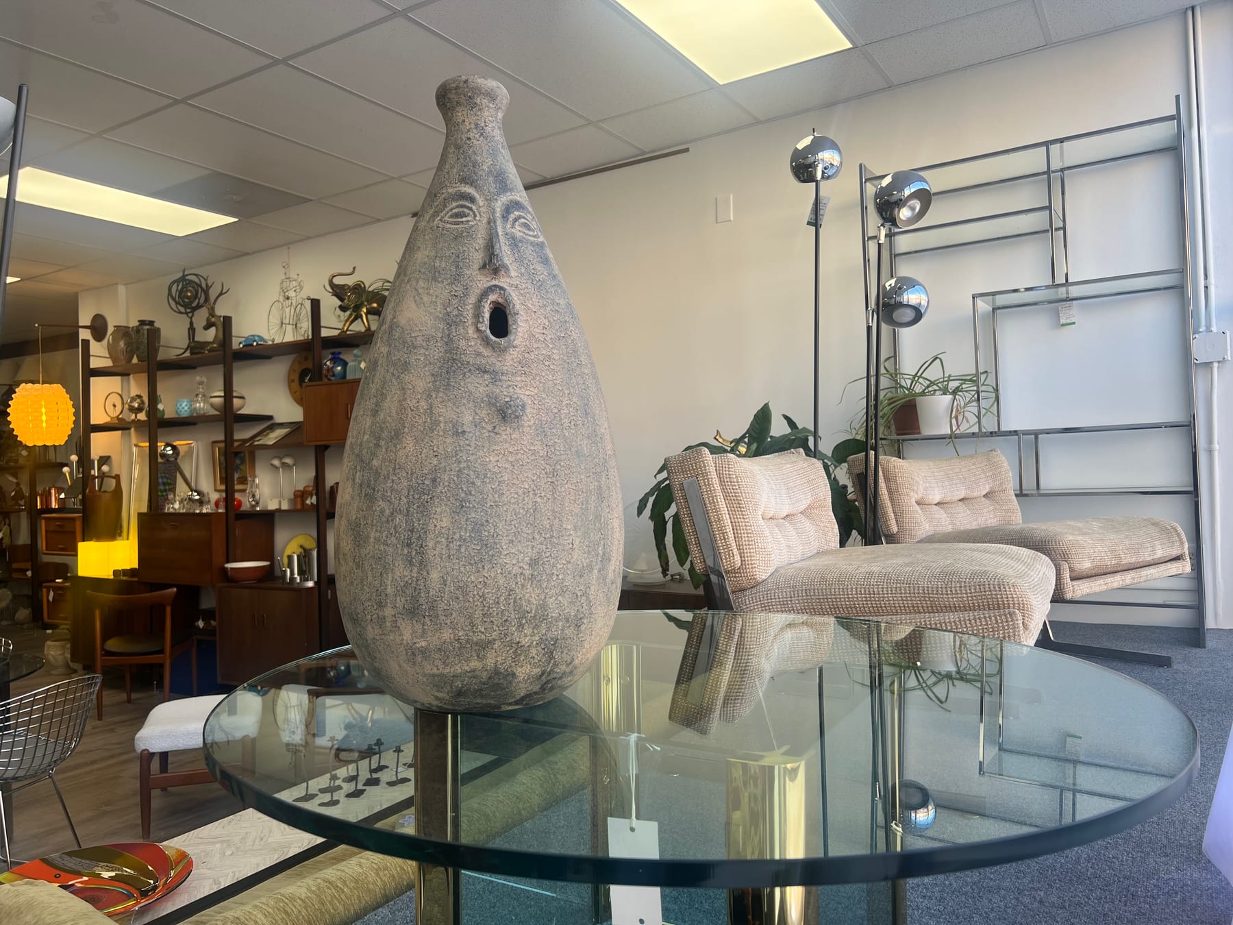 A tall ceramic face vessel set on a chrome-and-glass round dining table.